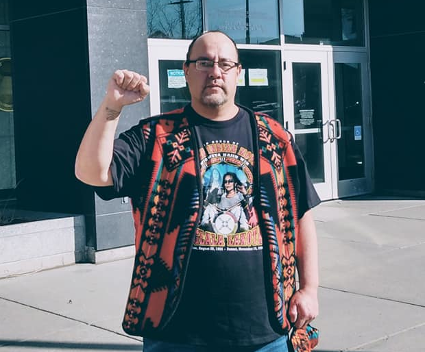 Steve Martinez raises fist in front of Federal Courthouse in Bismark, ND, 2021